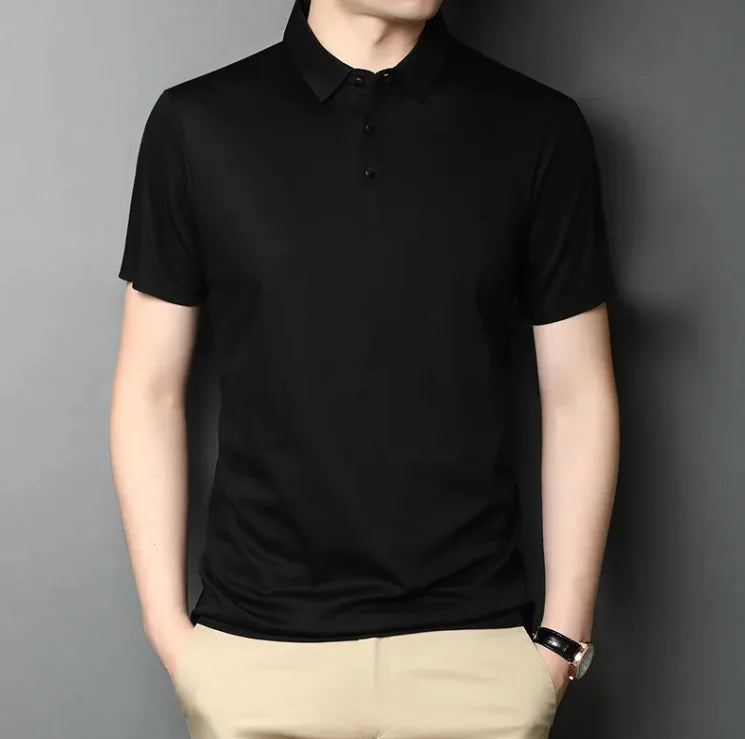 Man staat in een zwarte t-shirt met twee handen in zijn broekzakken.